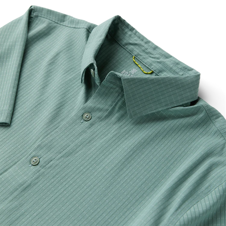 Close-up of a green polo shirt with collar and button details on a white background