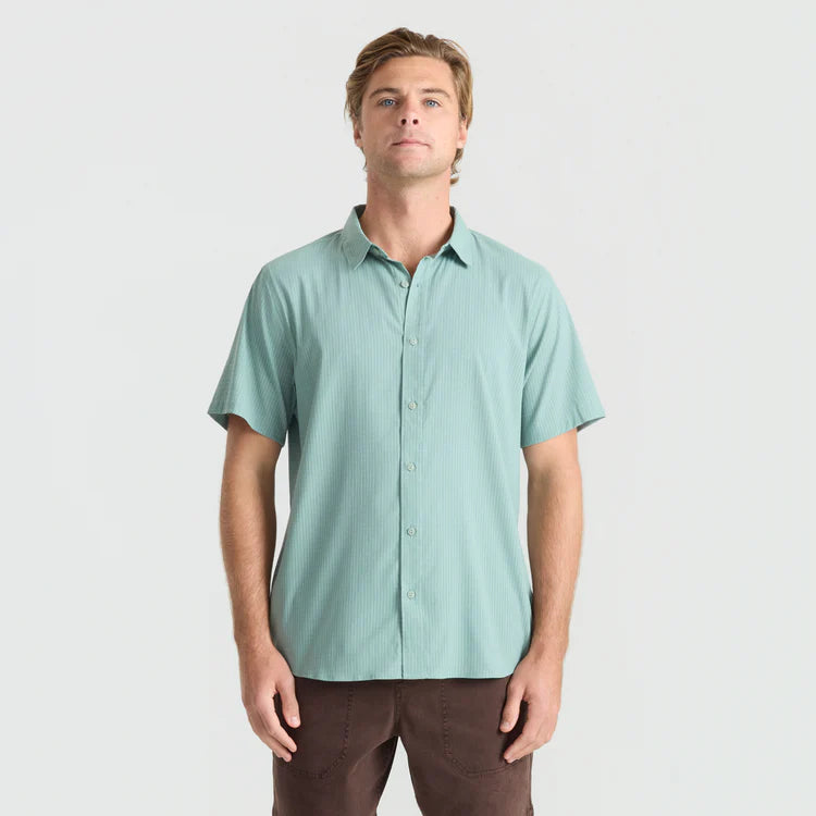 Man wearing a light green short-sleeve shirt on a plain background