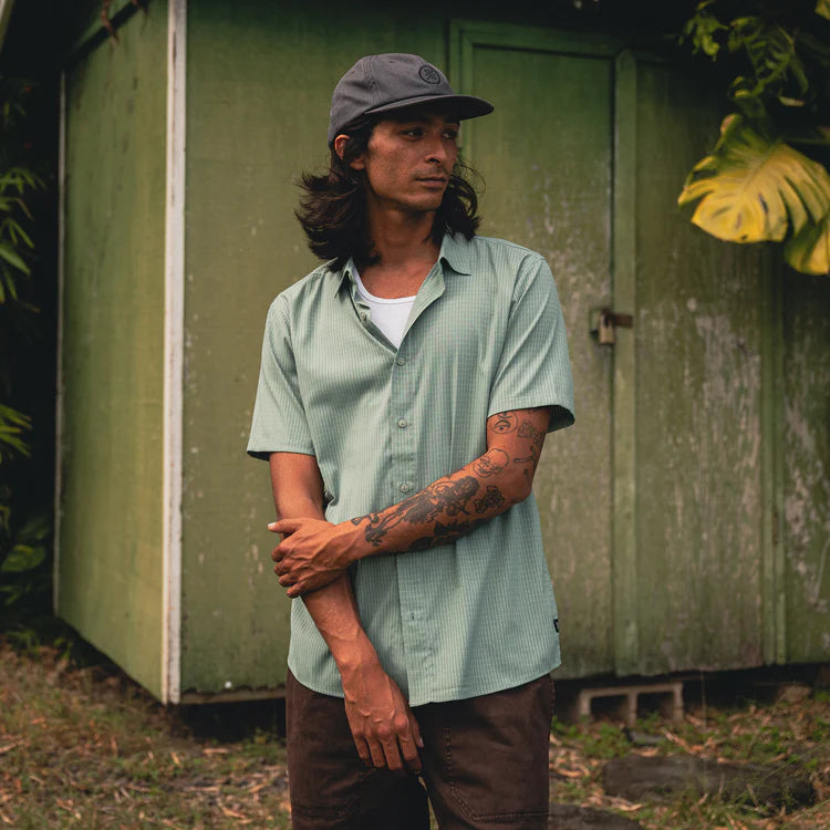 Man standing in front of a green shed with tattoos on his arms