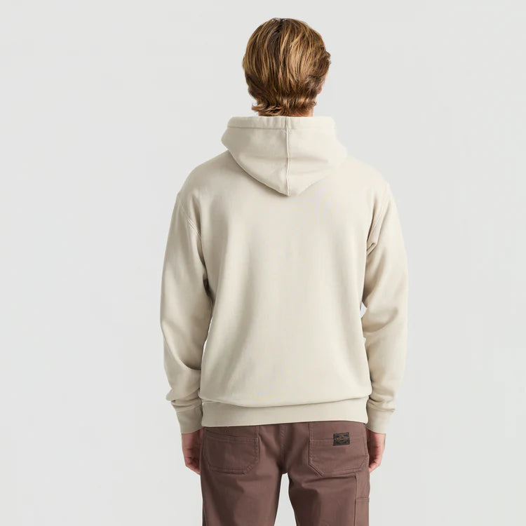 Person wearing a beige hoodie and brown pants on a light gray background