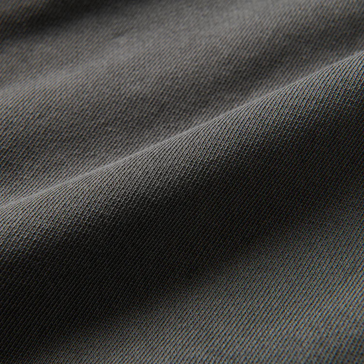 A close-up of dark gray textured fabric with a fine ribbed weave and soft folds.