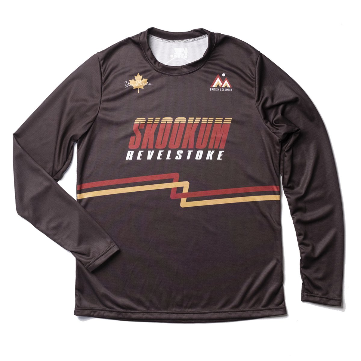 Brown long-sleeve shirt with 'Skookum Revelstoke' text and logos on a white background