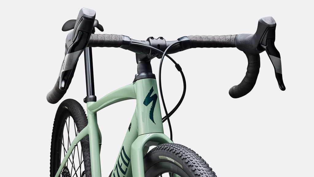 Close-up of a green bicycle with black handlebars on a light gray background