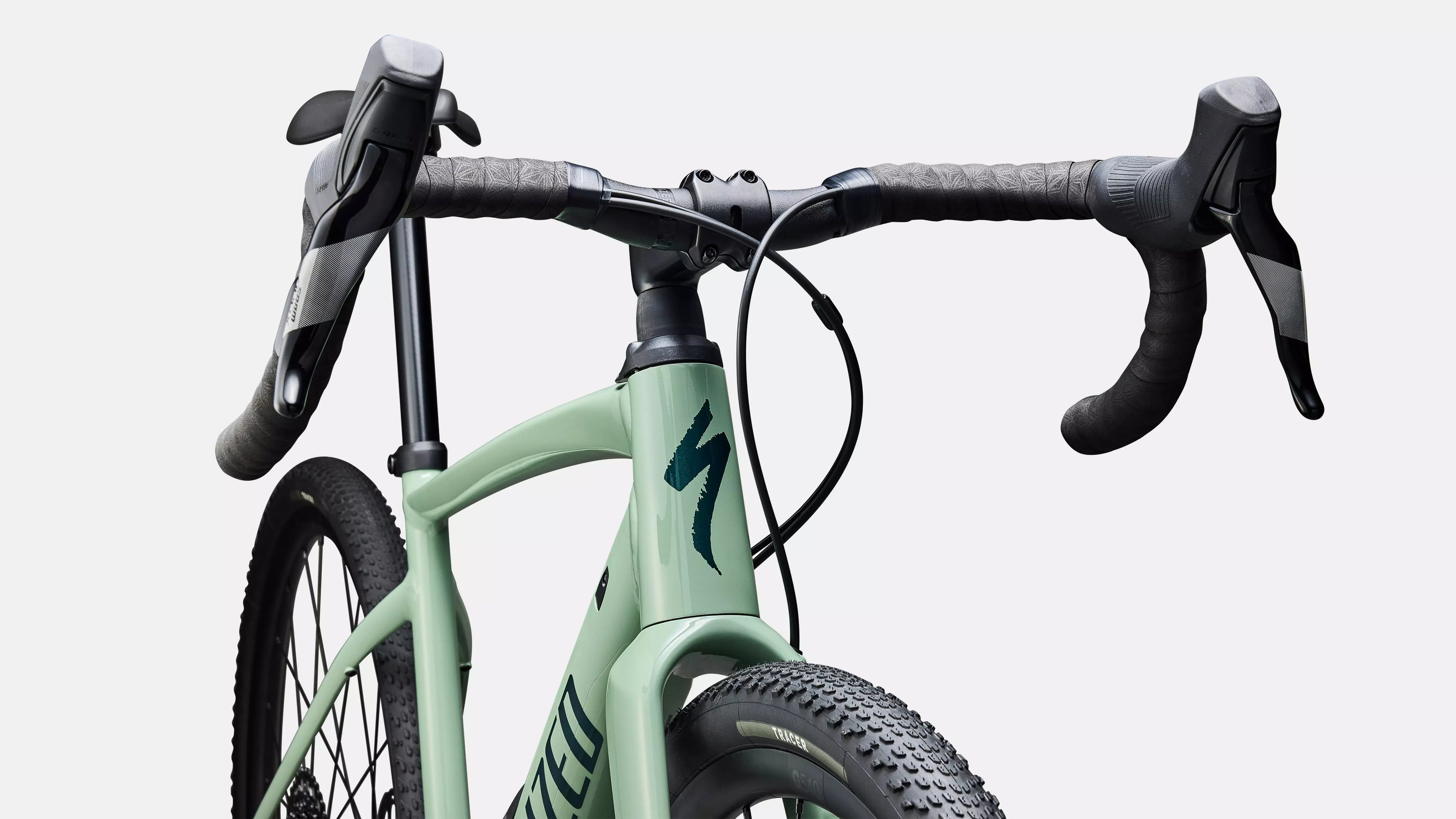 Close-up of a green bicycle with black handlebars on a light gray background