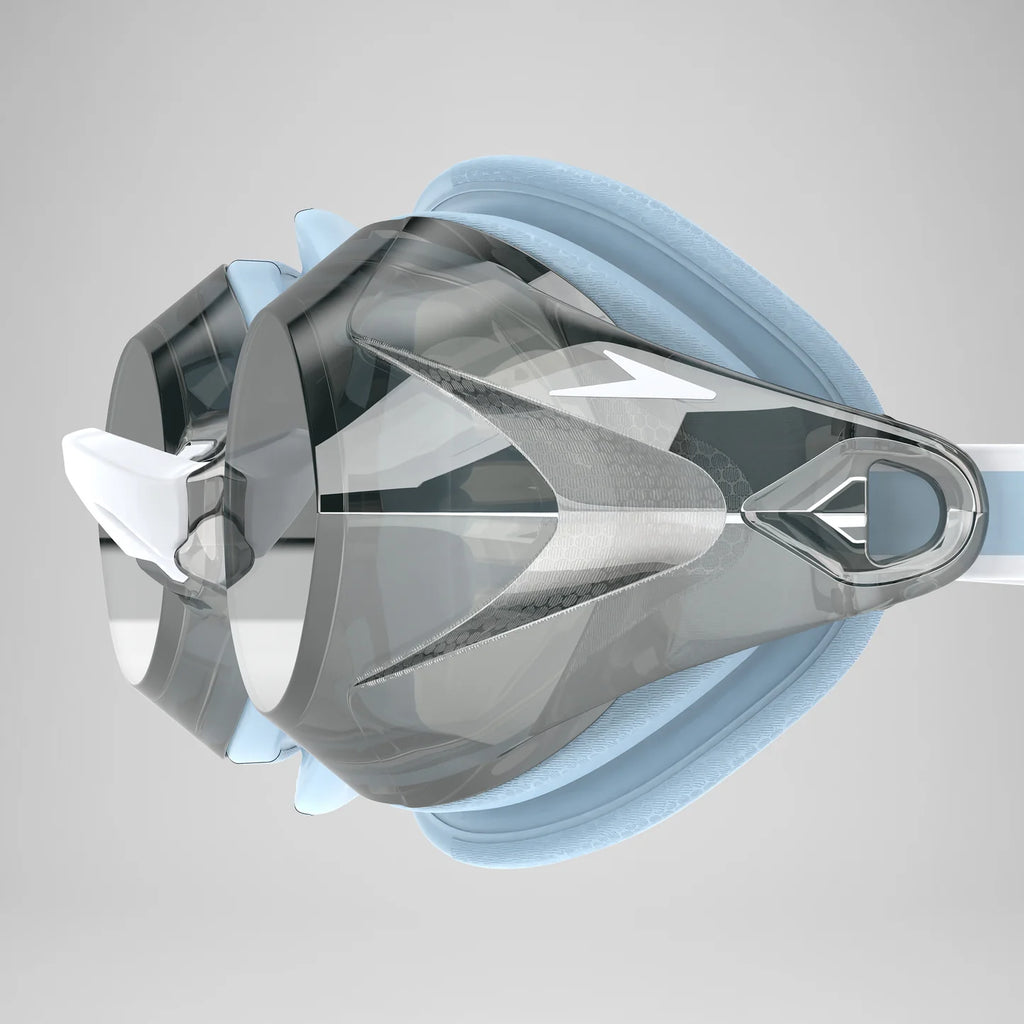 A close-up of a swim goggles with a transparent visor, light blue foam padding, and a white strap on a light gray background.