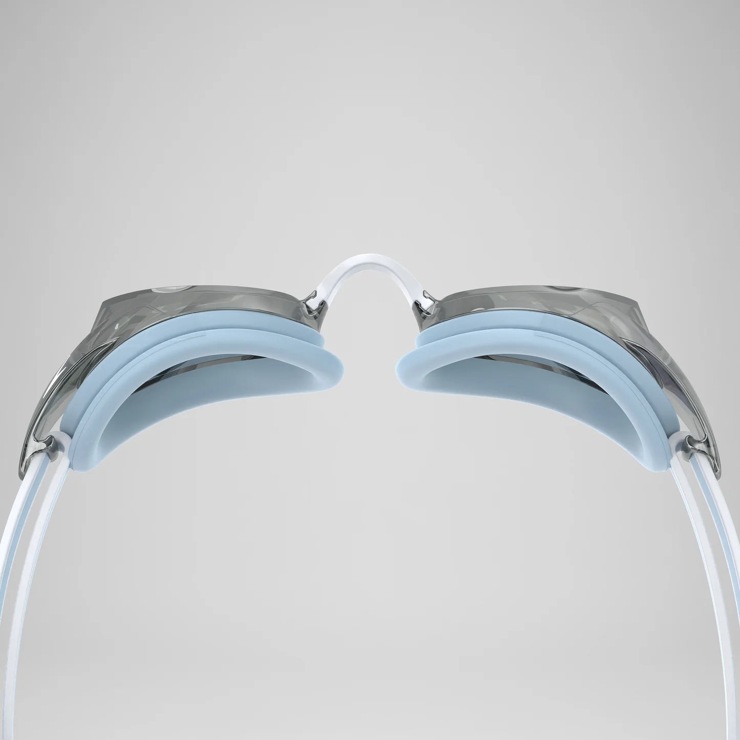 Close-up rear view of swimming goggles showing the white straps, light blue silicone pads, and metallic silver frame against a neutral gray background.