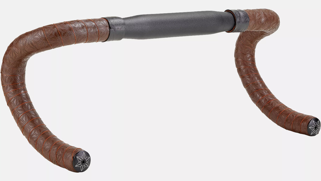 Brown leather handlebar tape wrapped around a drop-bar bicycle handlebar, with a dark gray foam center section and black end caps, shown on a plain light gray background.