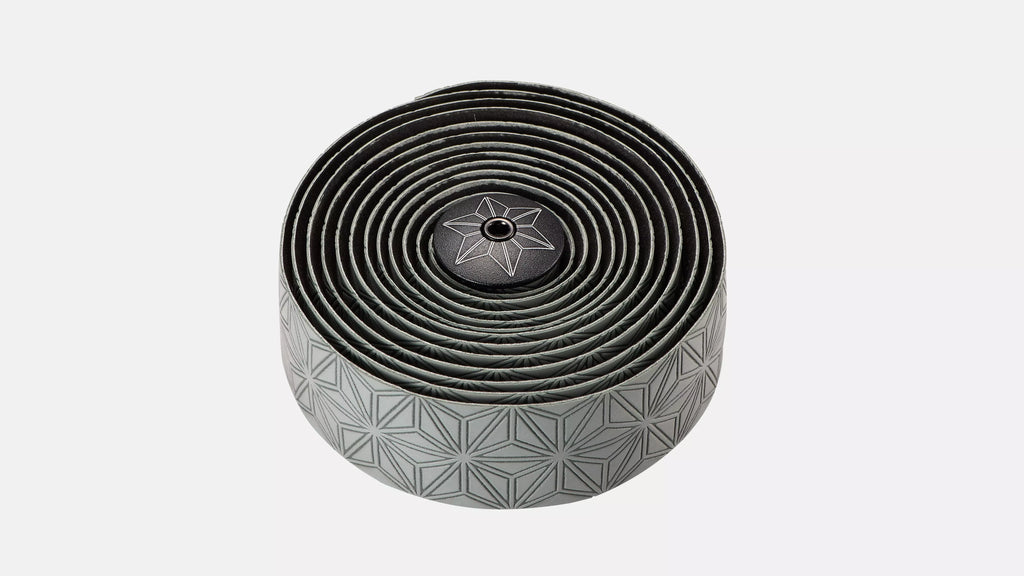 A rolled-up black bicycle tape with a geometric pattern on the outer layer and a central star emblem, shown on a light gray background.