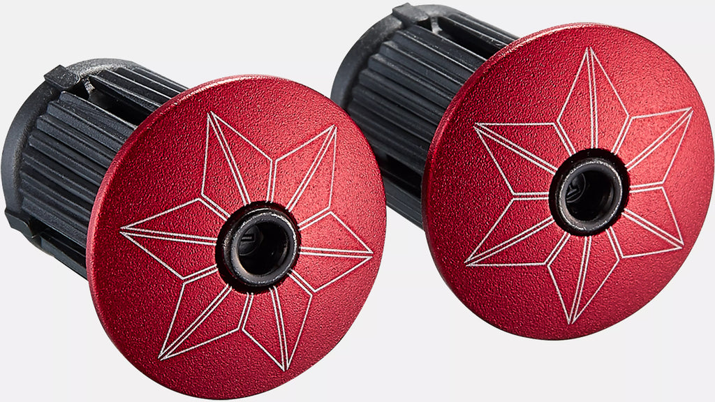 Two red metal buttons with star designs on a white background