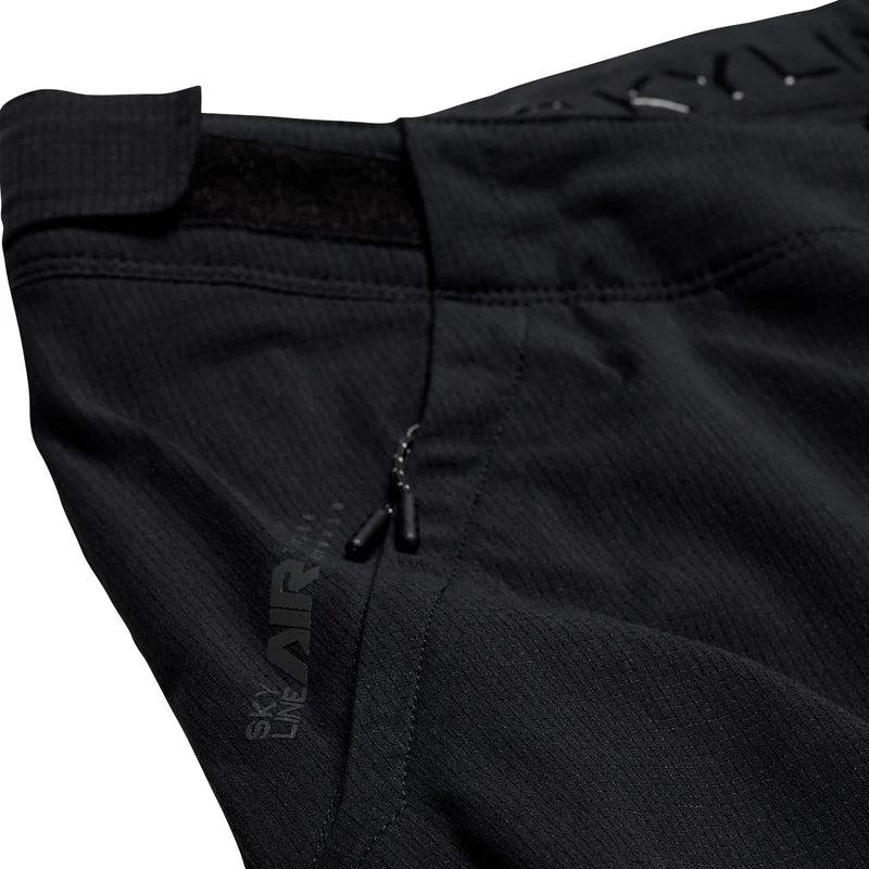 Close-up of black pants with a brand logo on a white background