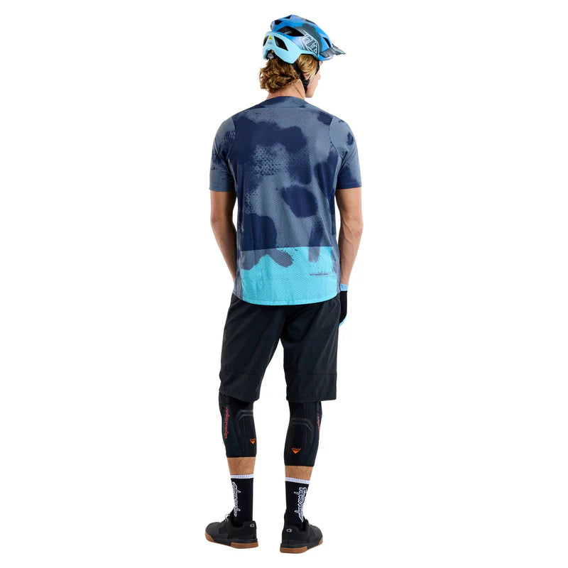 Person wearing a blue and gray cycling outfit with a helmet on a white background