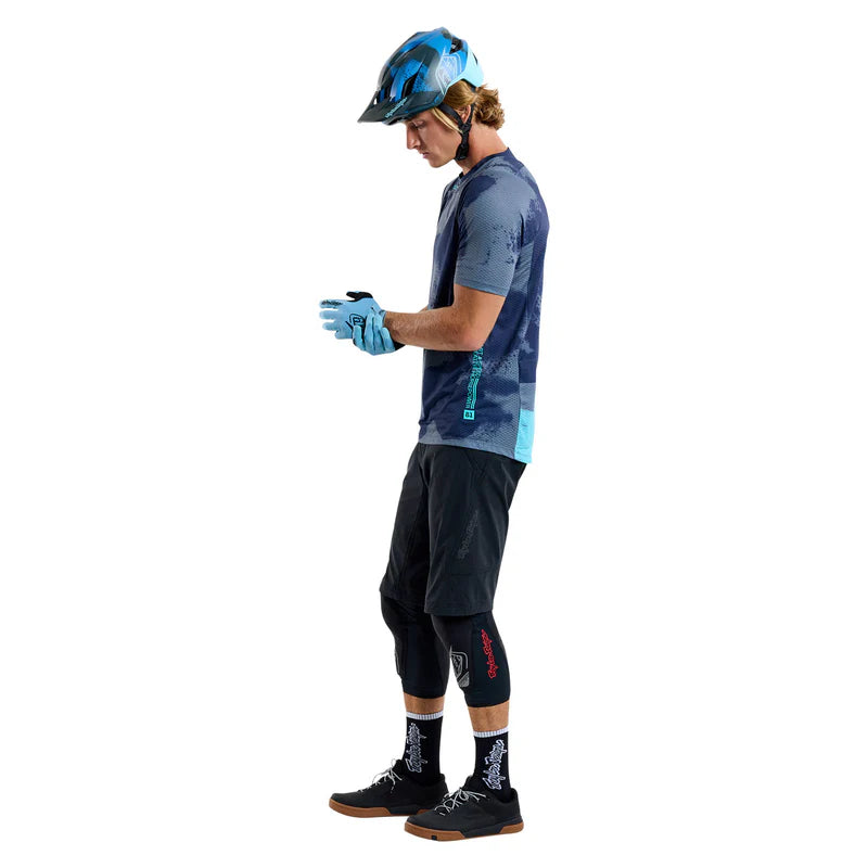Person wearing mountain biking gear including a helmet, jersey, shorts, and gloves on a white background