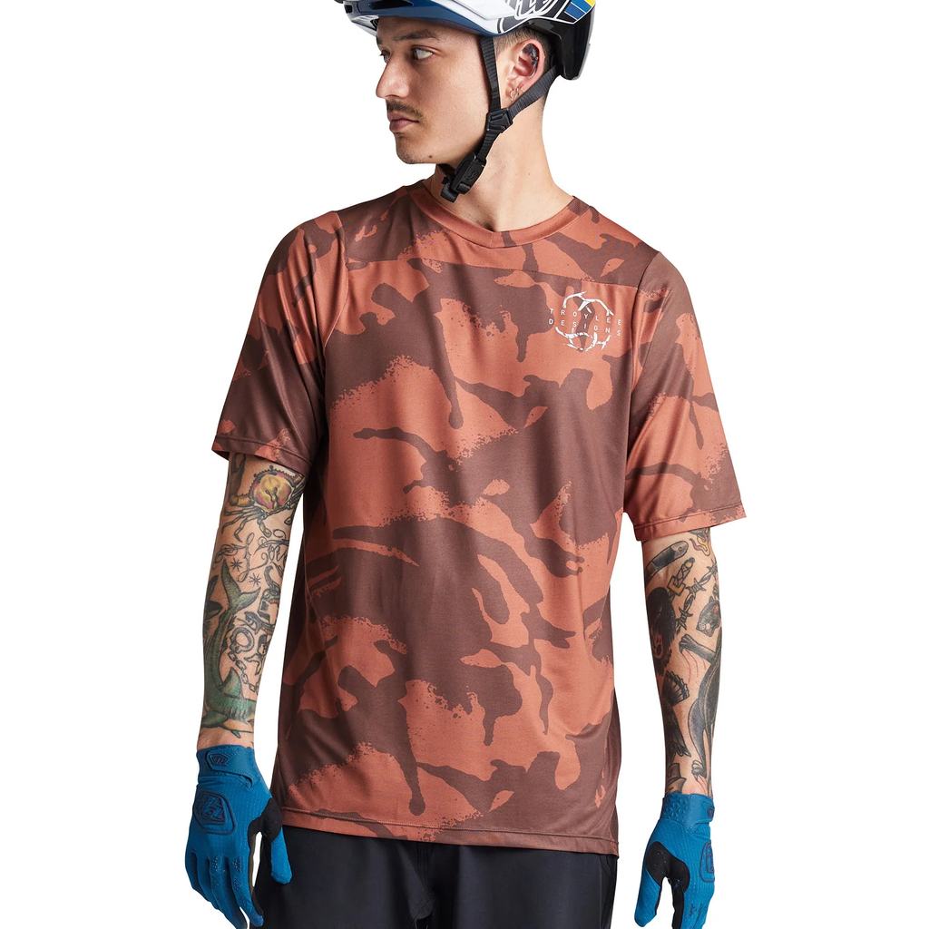 Person wearing a camouflage t-shirt, helmet, and gloves on a white background