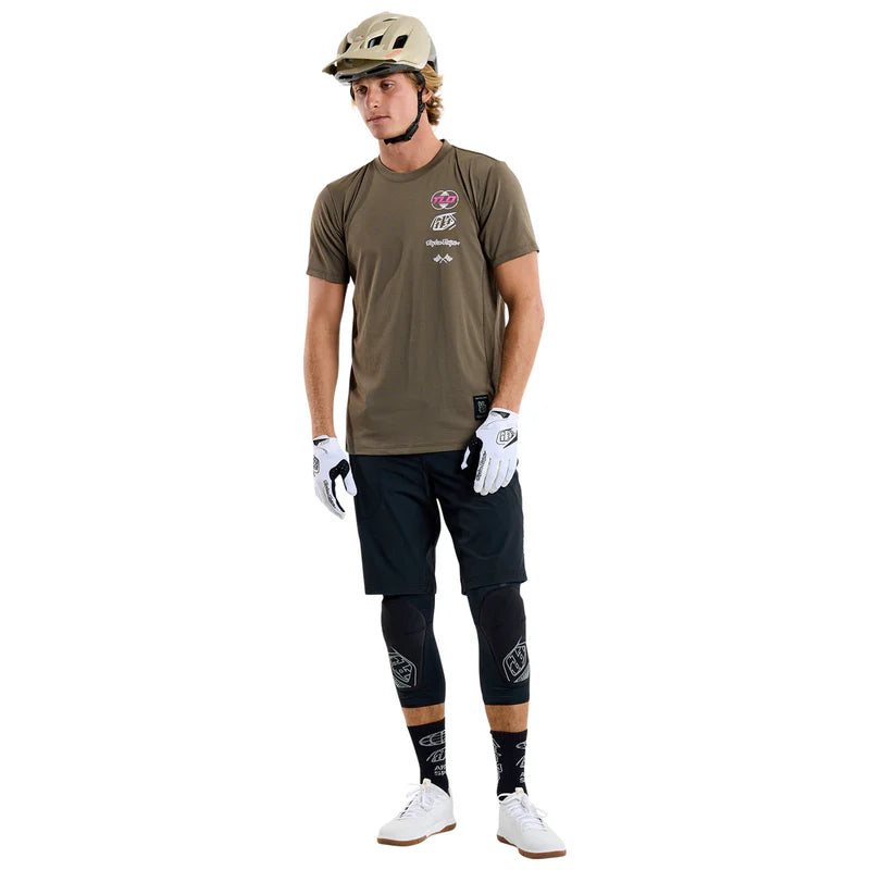 Person wearing a brown t-shirt, black pants, white gloves, and a helmet on a white background
