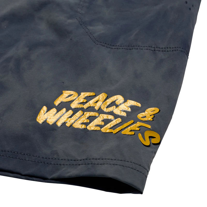Text 'PEACE & WHEELIES' embroidered on a dark fabric background