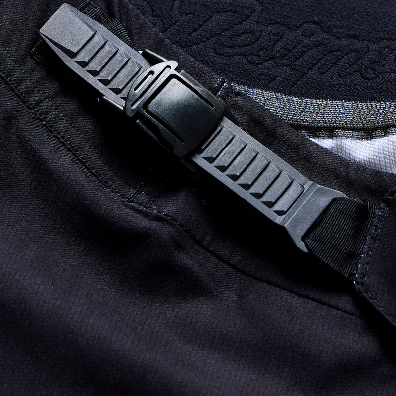 Close-up of a black belt with a textured buckle on a dark fabric background
