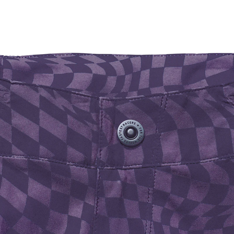 Close-up of a purple checkered fabric with a button, featuring a brand logo.