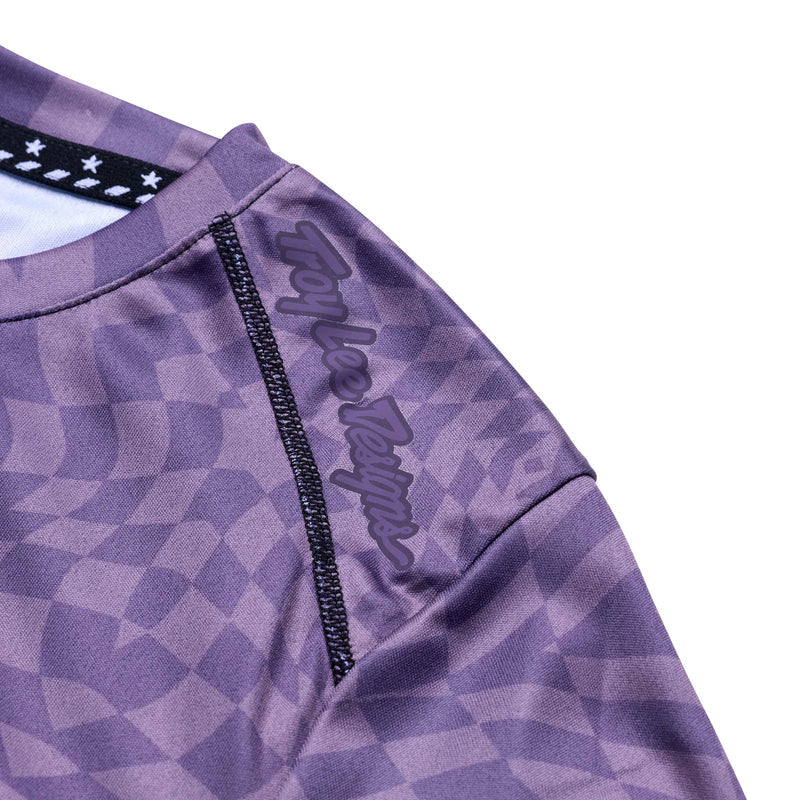 Close-up of a purple checkered shirt with a brand logo on a white background