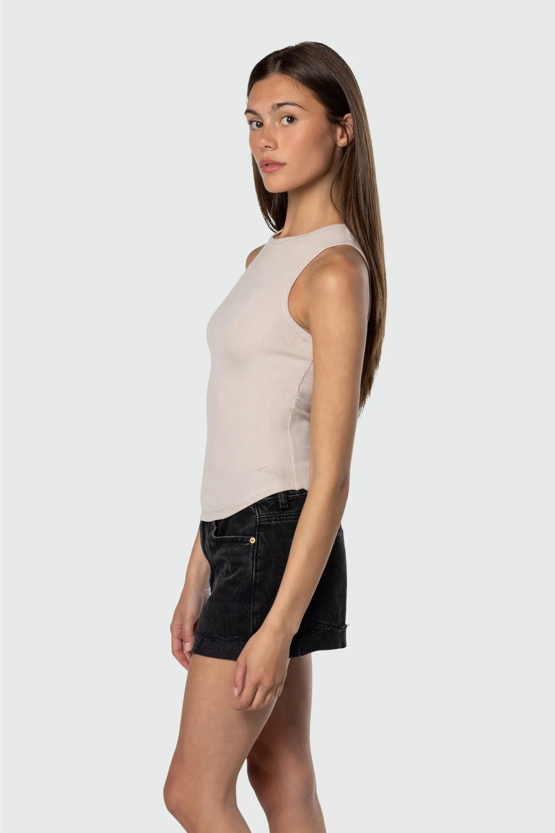 Woman wearing a beige sleeveless top and black shorts on a white background
