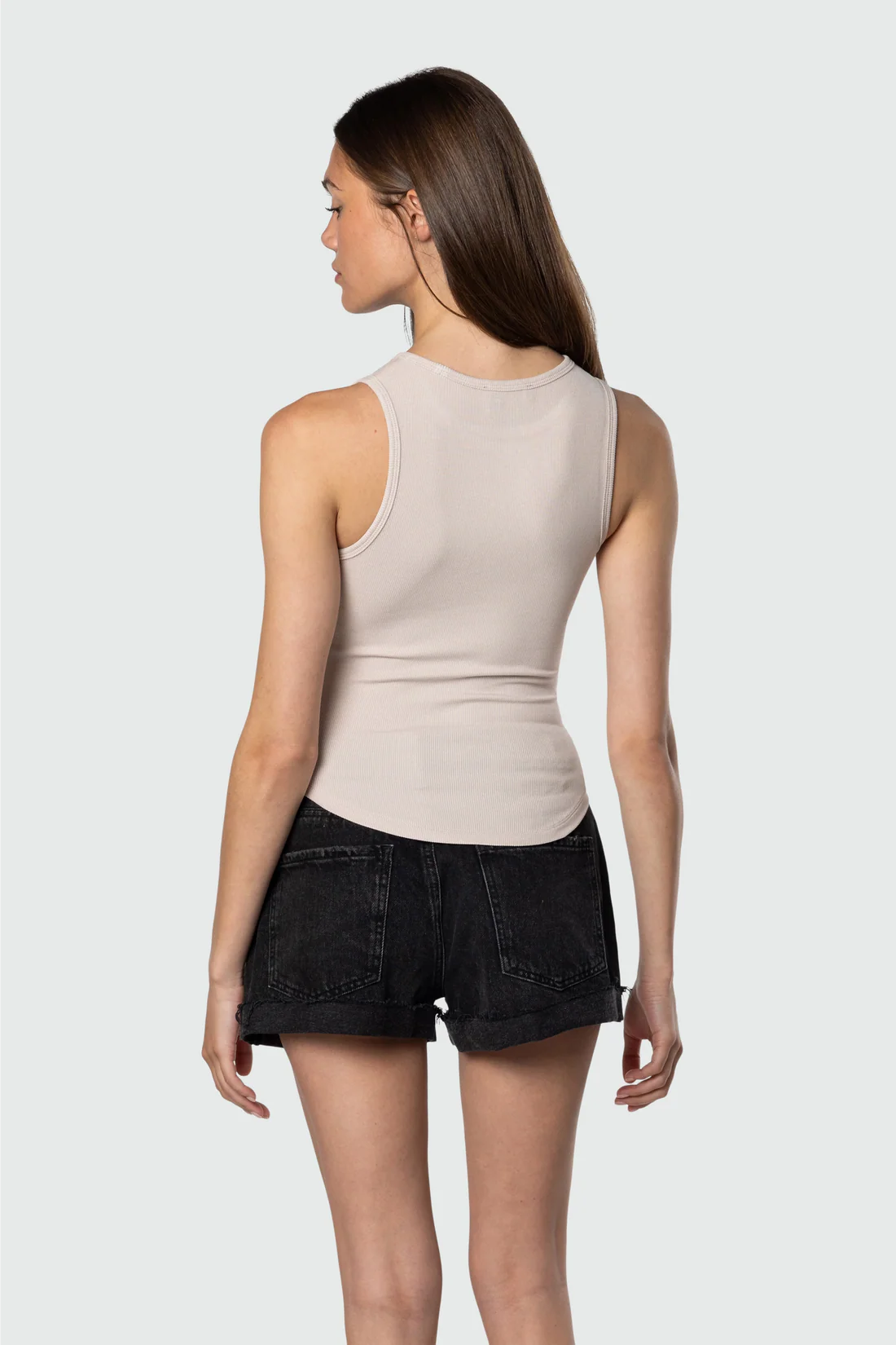 Woman wearing a beige tank top and black shorts on a white background