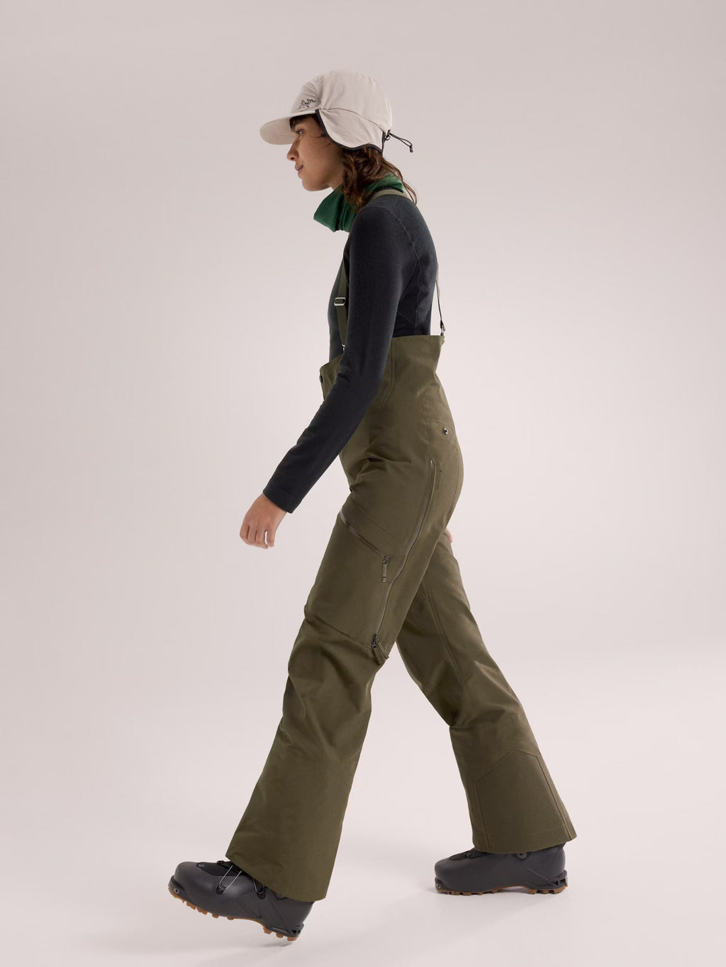 Person wearing green overalls and a cap on a white background