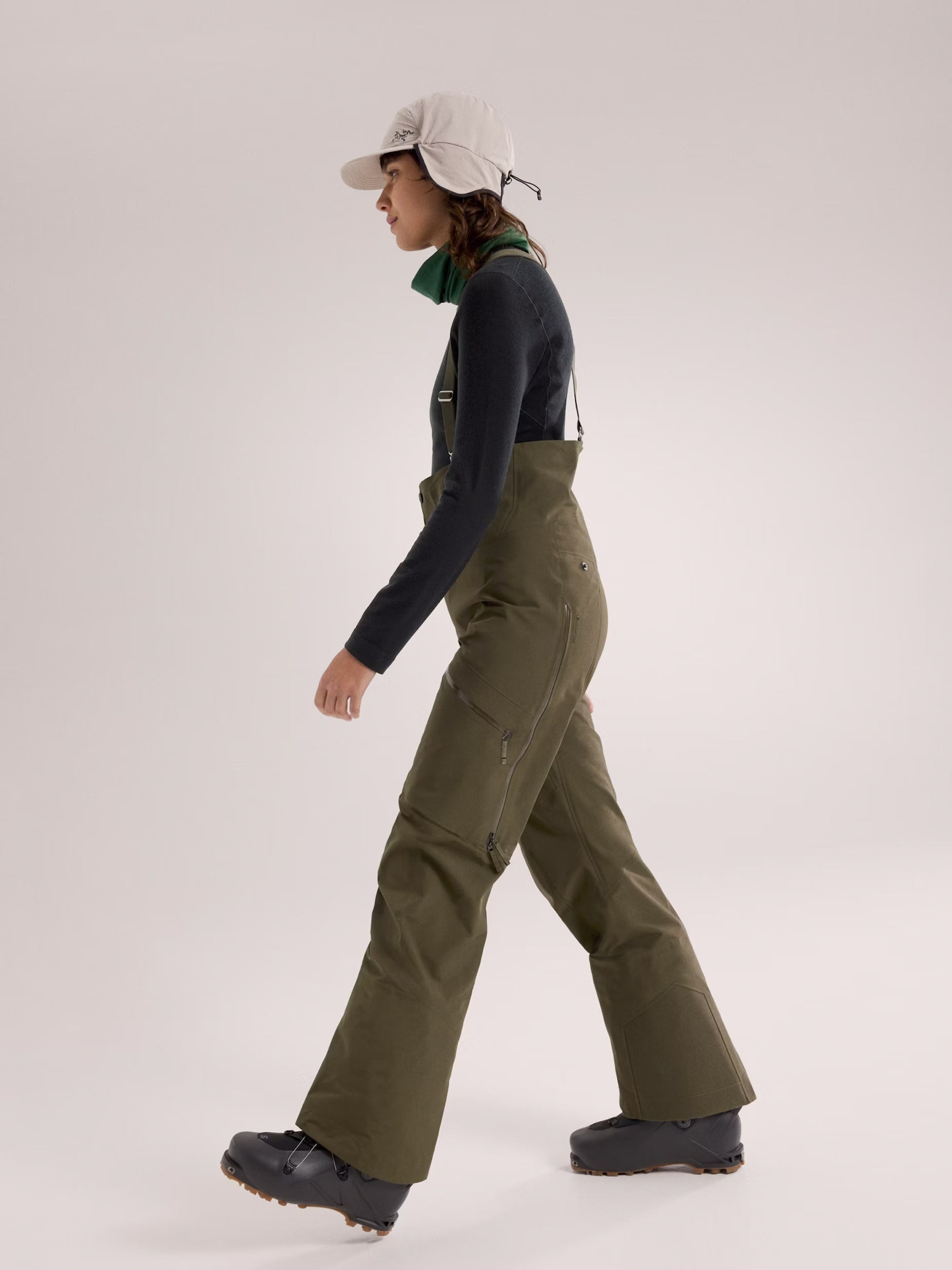 Person wearing green overalls and a cap on a white background