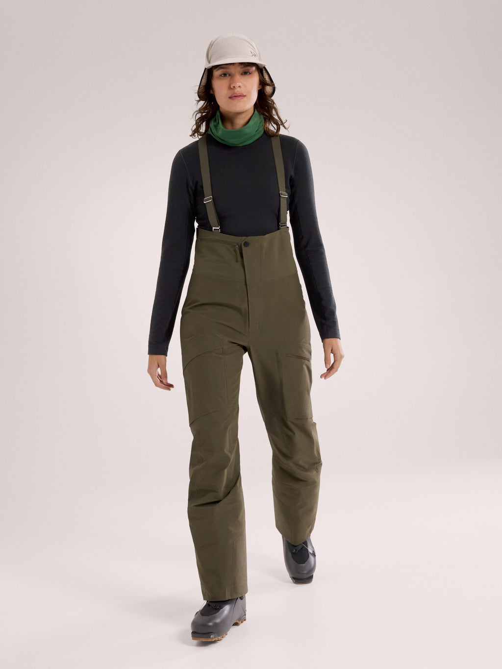 Person wearing green bib overalls on a white background