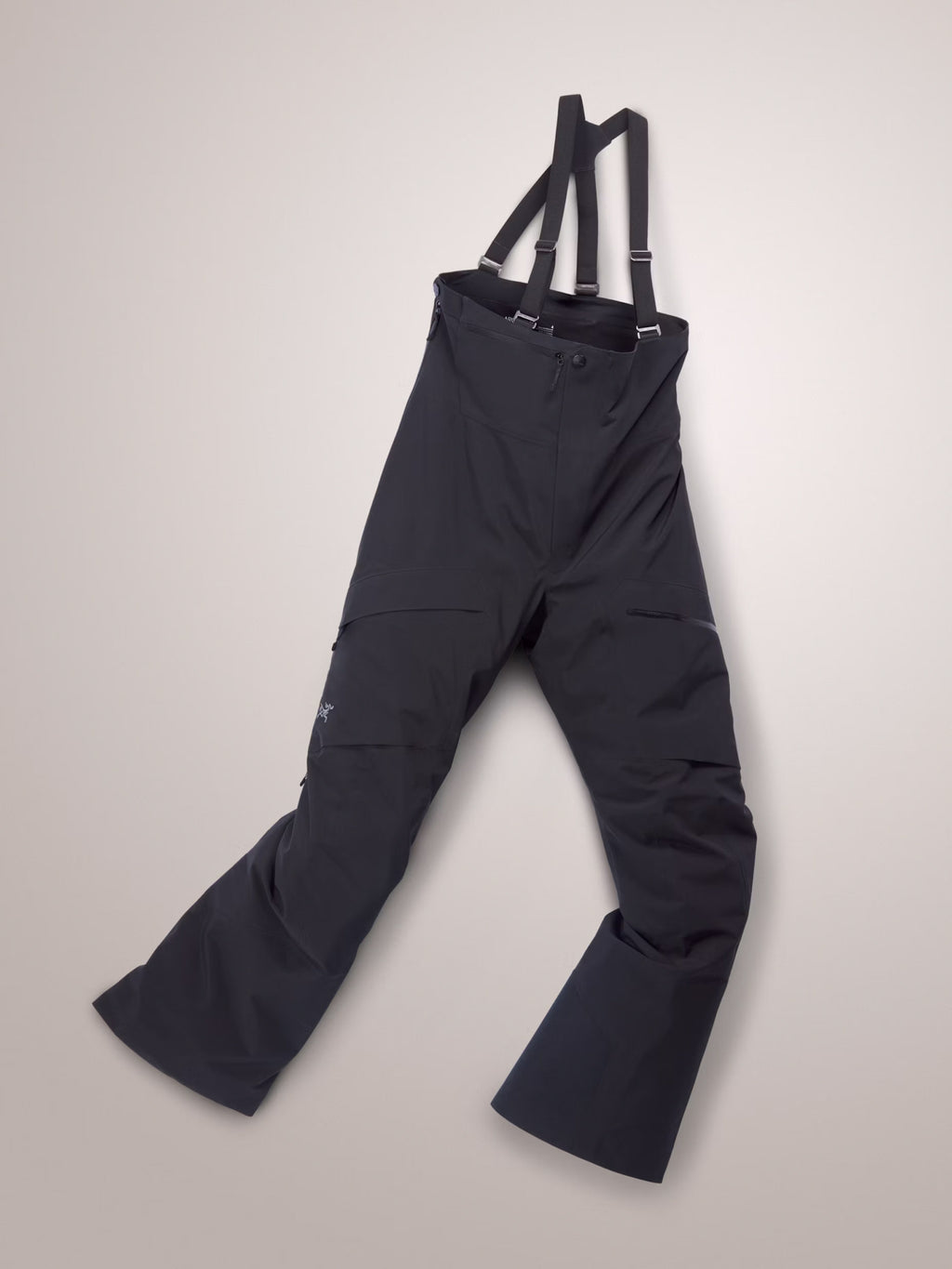 Navy blue bib overalls with suspenders on a light gray background