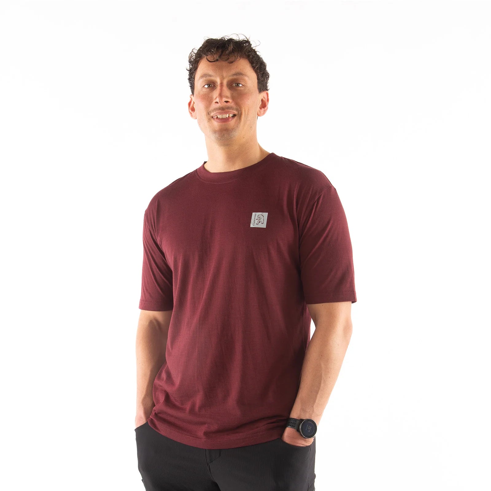 Man wearing a maroon t-shirt with a small logo on a white background