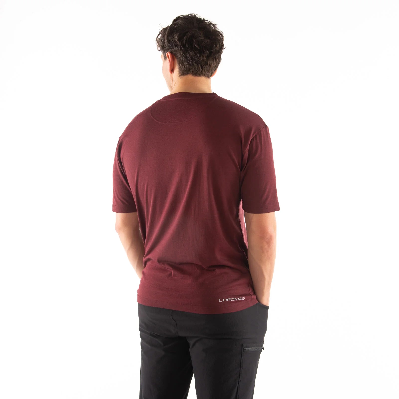 Man wearing a maroon t-shirt with a visible brand logo on the back, standing against a white background.