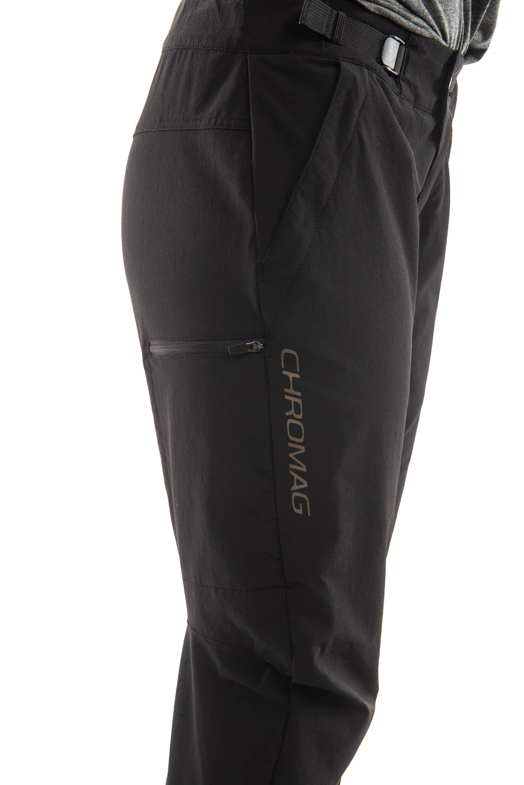 Close-up side view of black outdoor pants with a zippered pocket and vertical CHROMAG branding on the lower leg, shown against a white background.