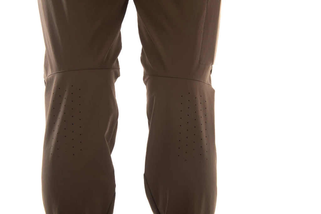 Close-up of a pair of brown technical pants or waders with perforated leg panels, shown against a plain white background.