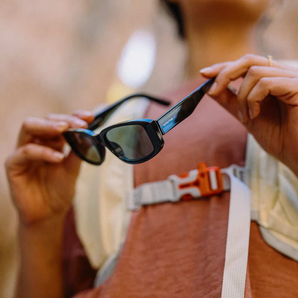Person holding a pair of sunglasses with a blurred background