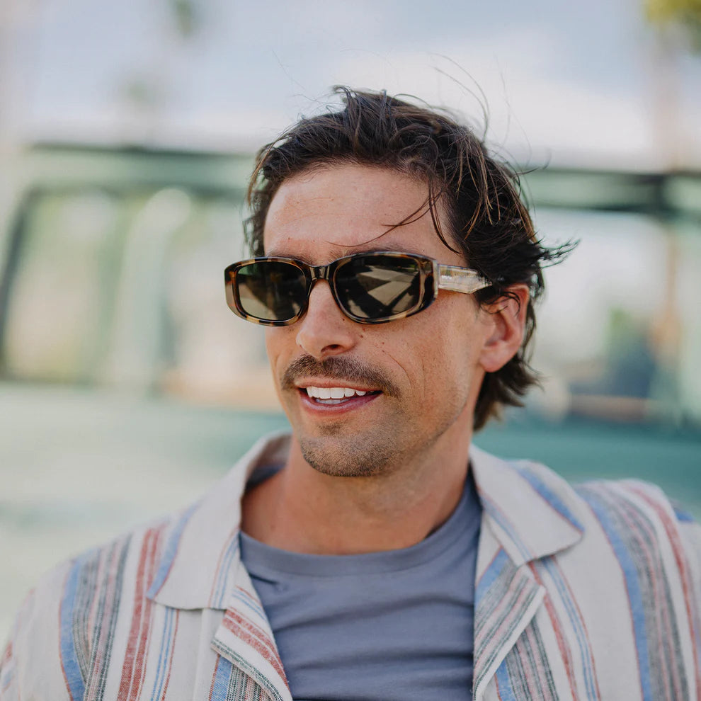 Man wearing sunglasses and a patterned jacket outdoors