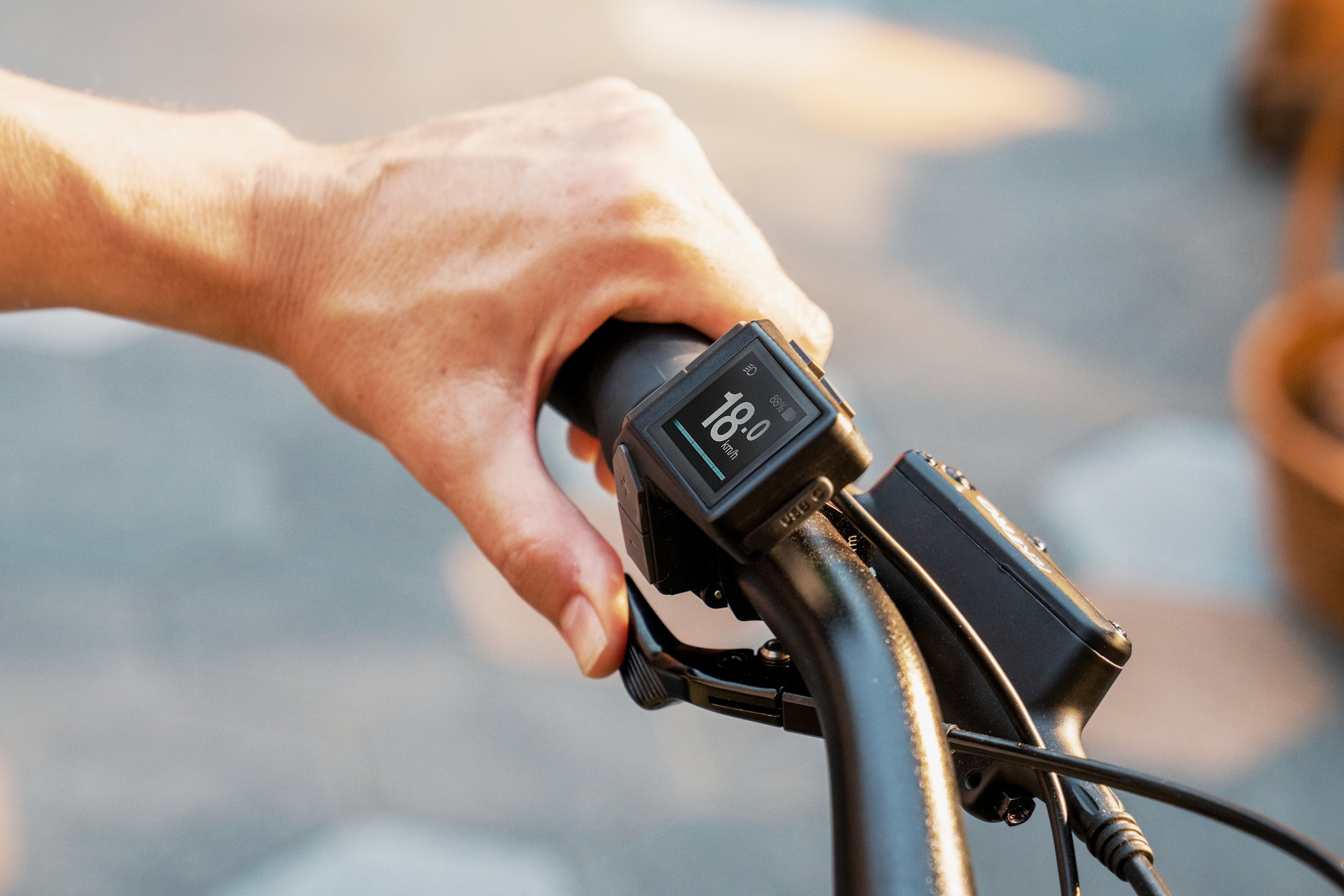 Hand holding a bike handlebar with electronic device displaying '180' on a blurred background