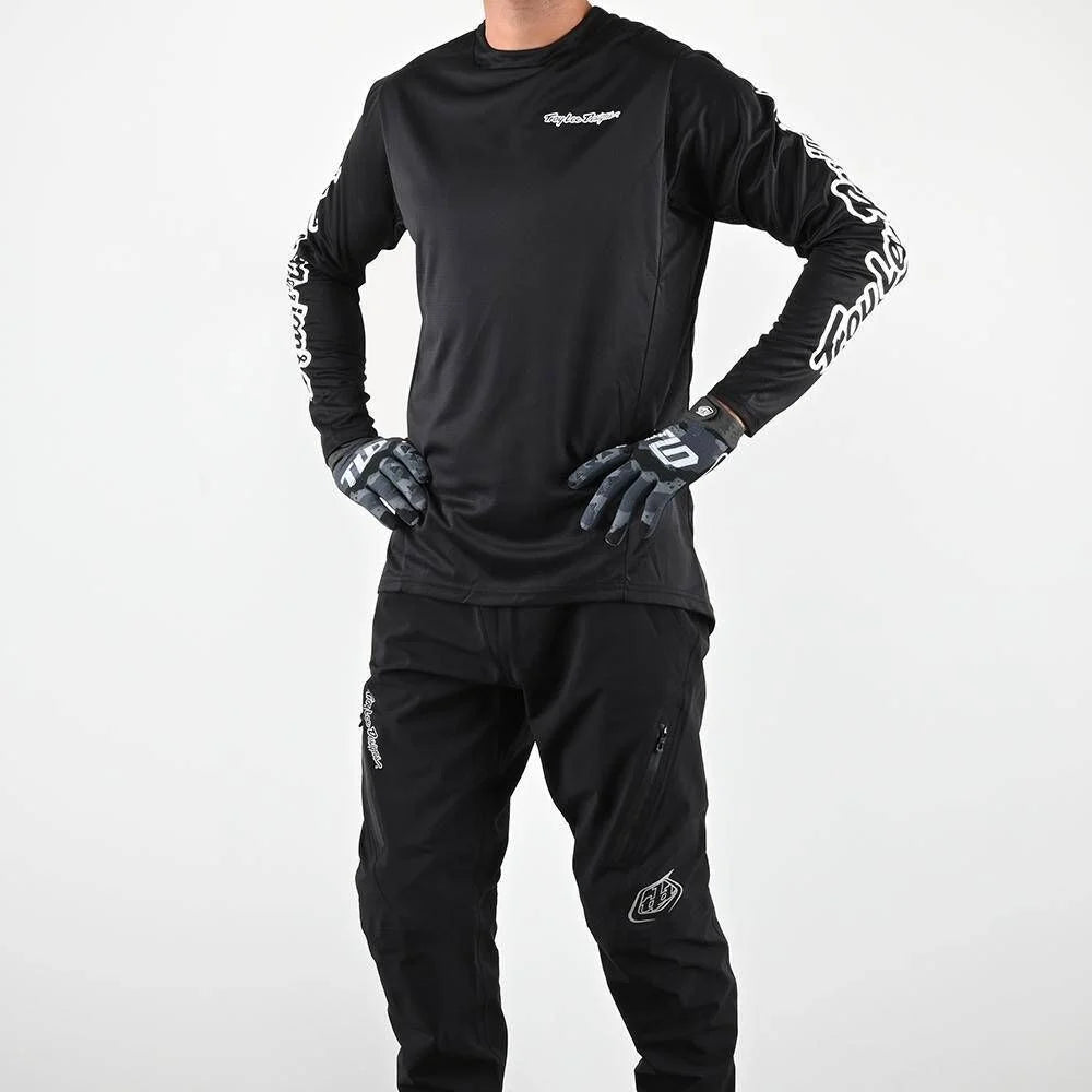 Person wearing a black motocross outfit with gloves on a white background